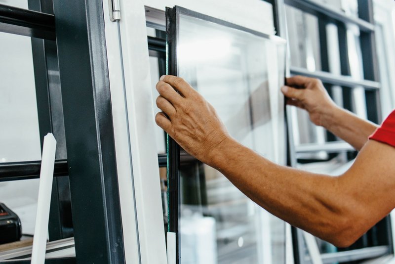 Fotografie eines Handwerkers beim einsetzen eines Glaspakets in den Fensterrahmen